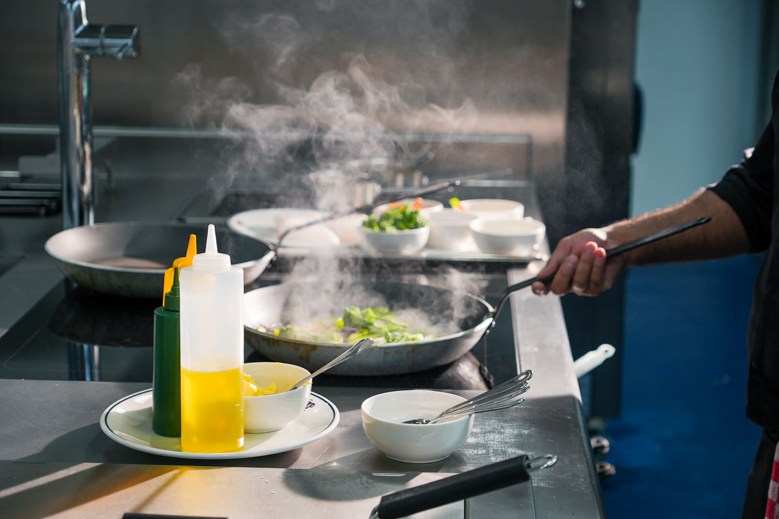 A chef working over steaming pans during a hotel production